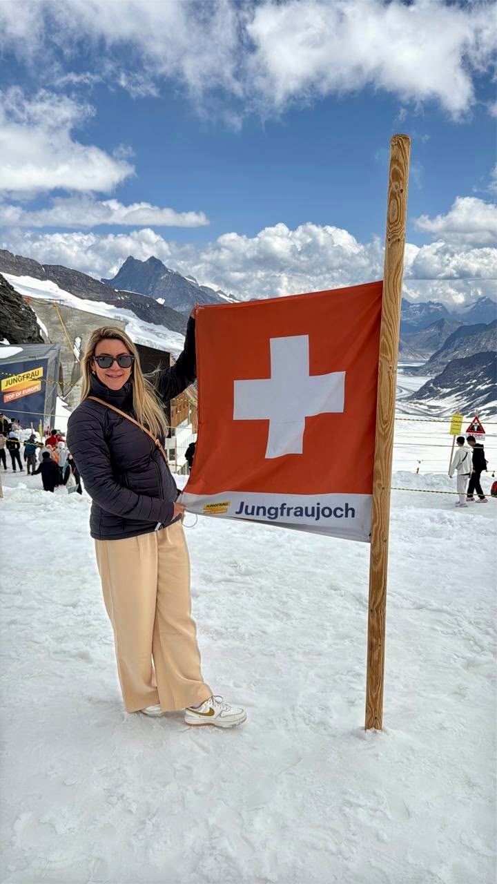 Carolina Andrade ao lado da bandeira suíça no Jungfraujoch, nos Alpes